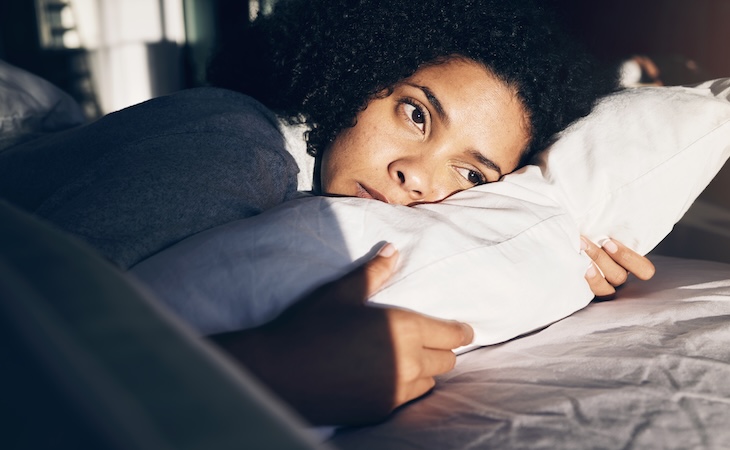 Person resting with pillows in bed.