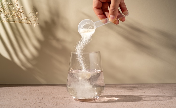 Hand pouring collagen powder into water